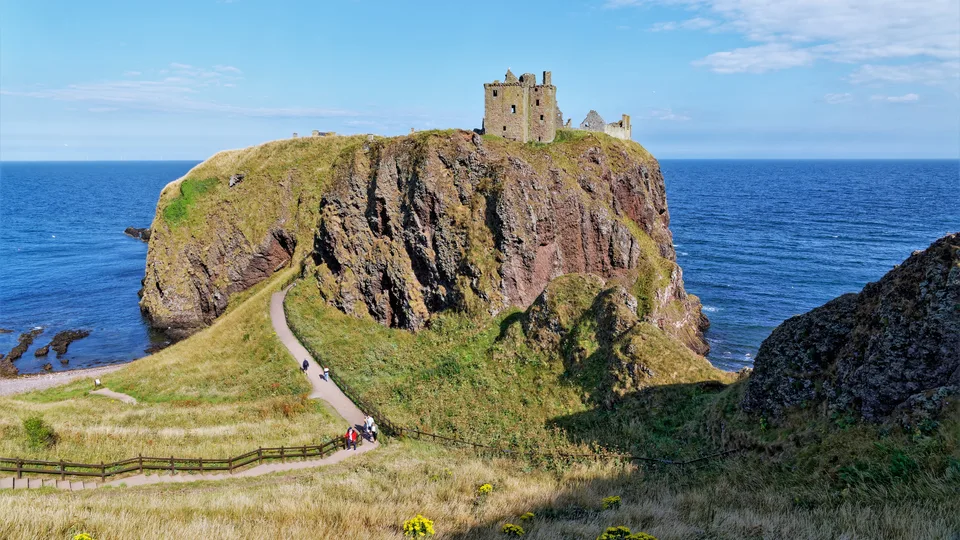 Dunnottar Castle on its clifftop headland south of Stonehaven, with walkers on the path down